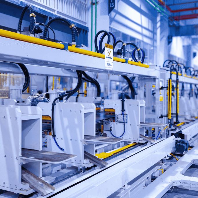 Automated manufacturing line with robotic stations and yellow safety rails in a spacious factory.