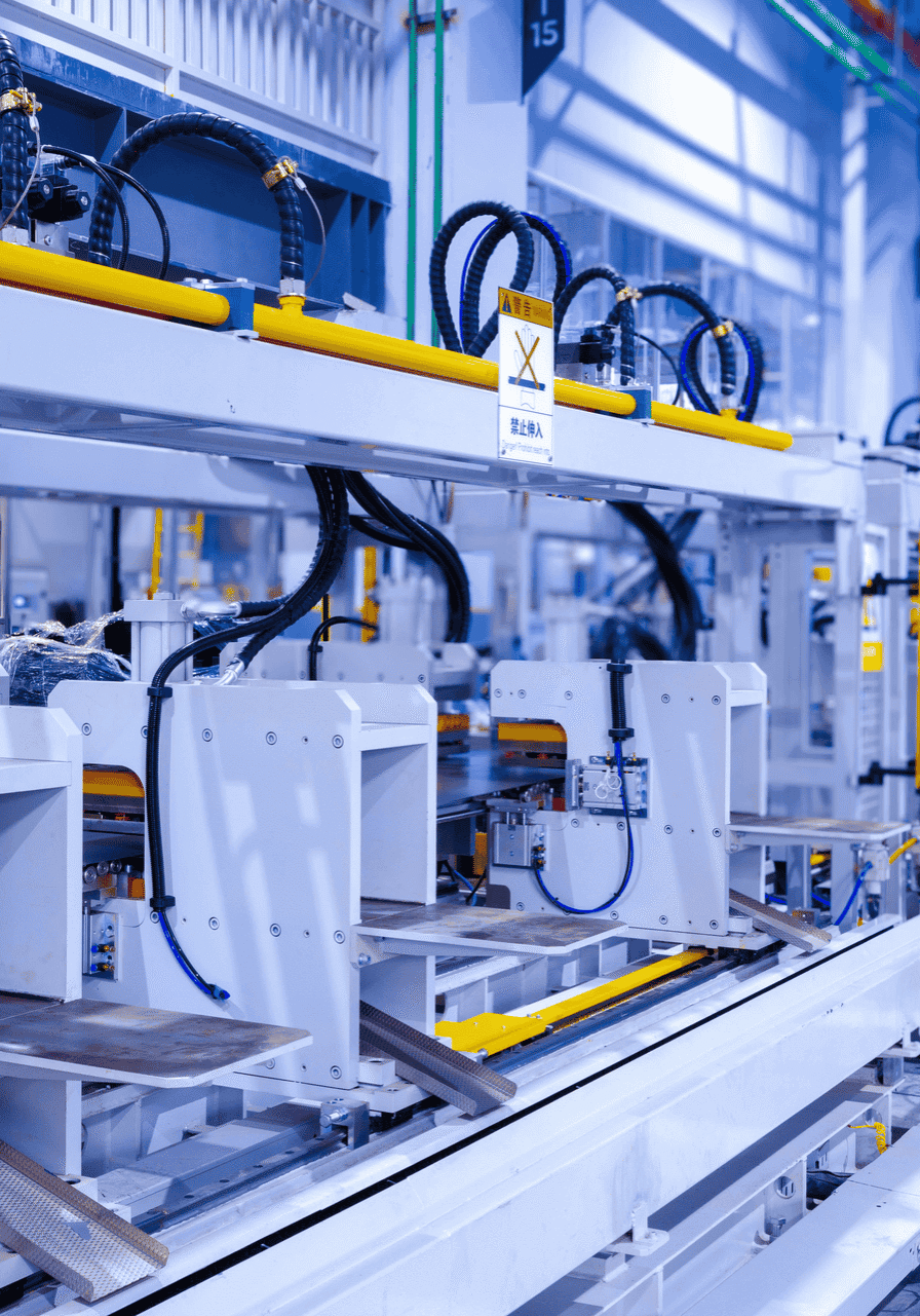 Automated manufacturing line with white machines, yellow safety rails, and black cables in a bright industrial facility